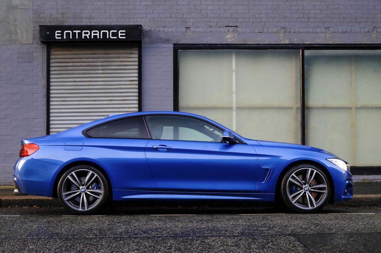 Blue sports car parked outside a grey brick building entrance