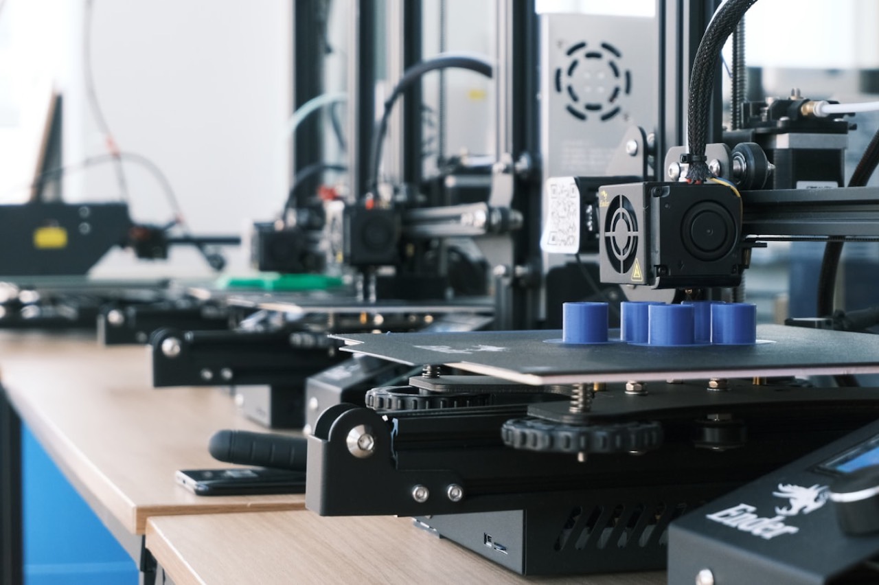 Row of Creality Ender 3D printers on a workbench with blue cylindrical prints