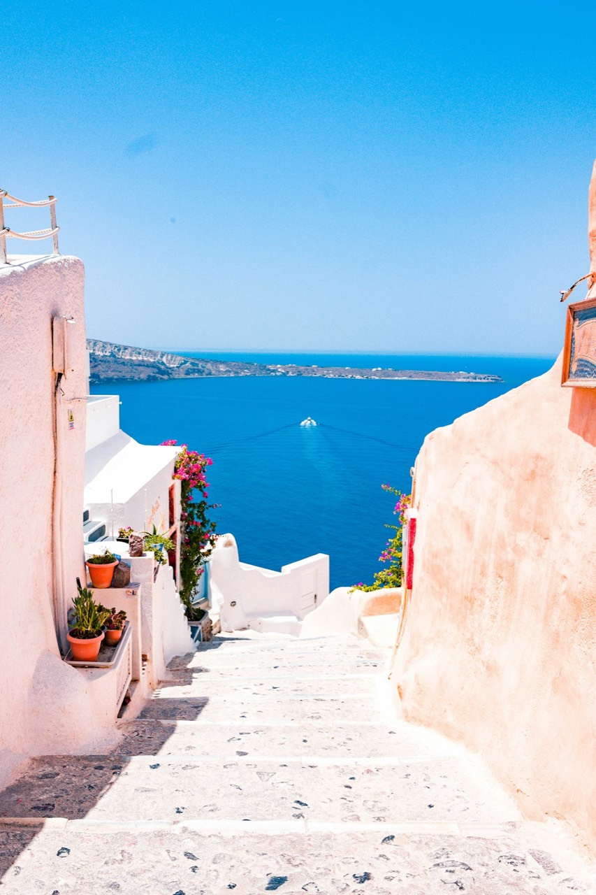 Whitewashed clifftop village steps leading down to blue Mediterranean water