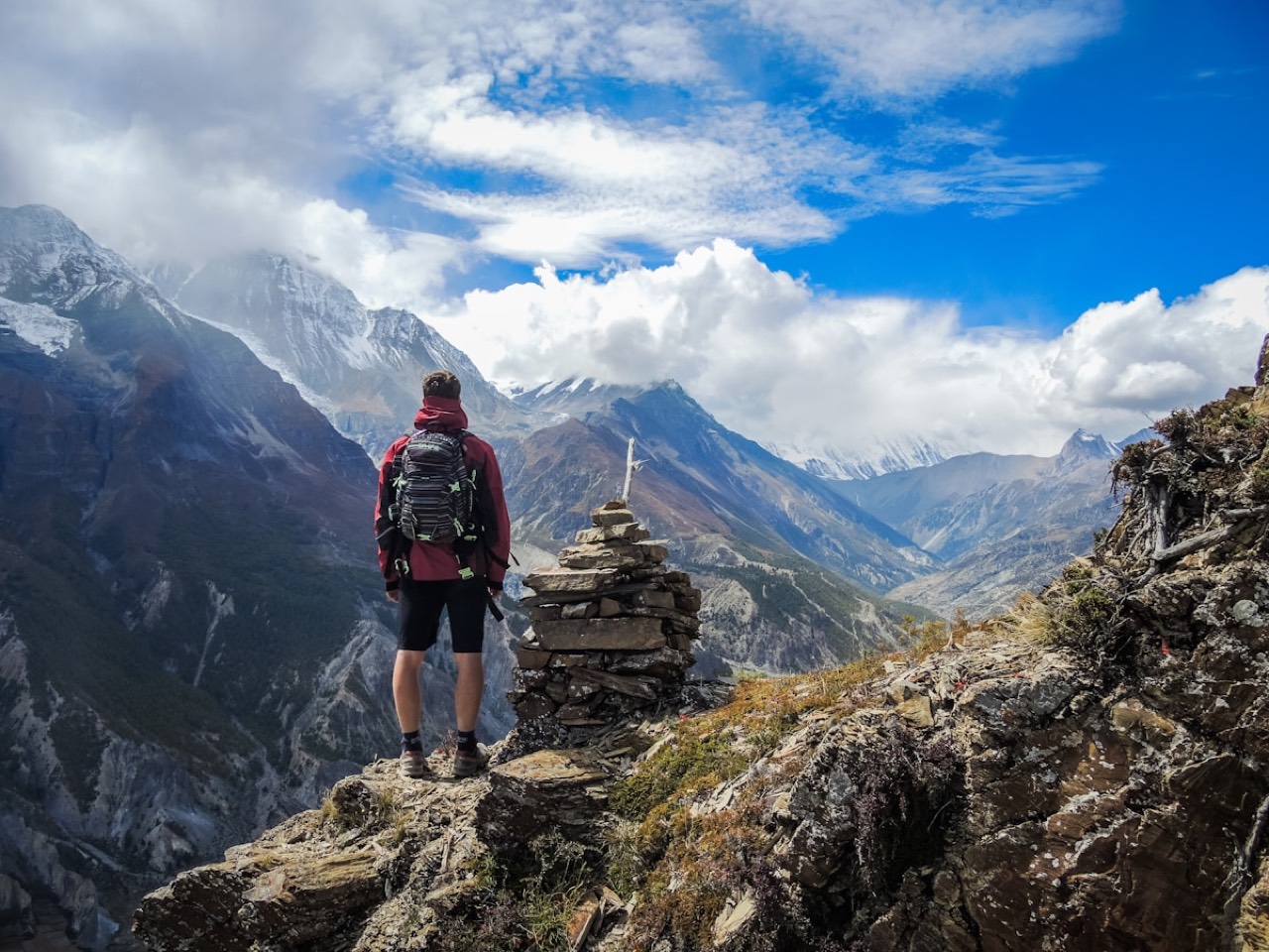 Hiker with a red backpack looking out over an Andean mountain range
