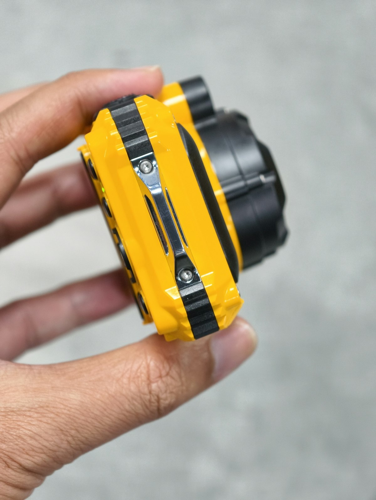 A hand holding a compact action camera