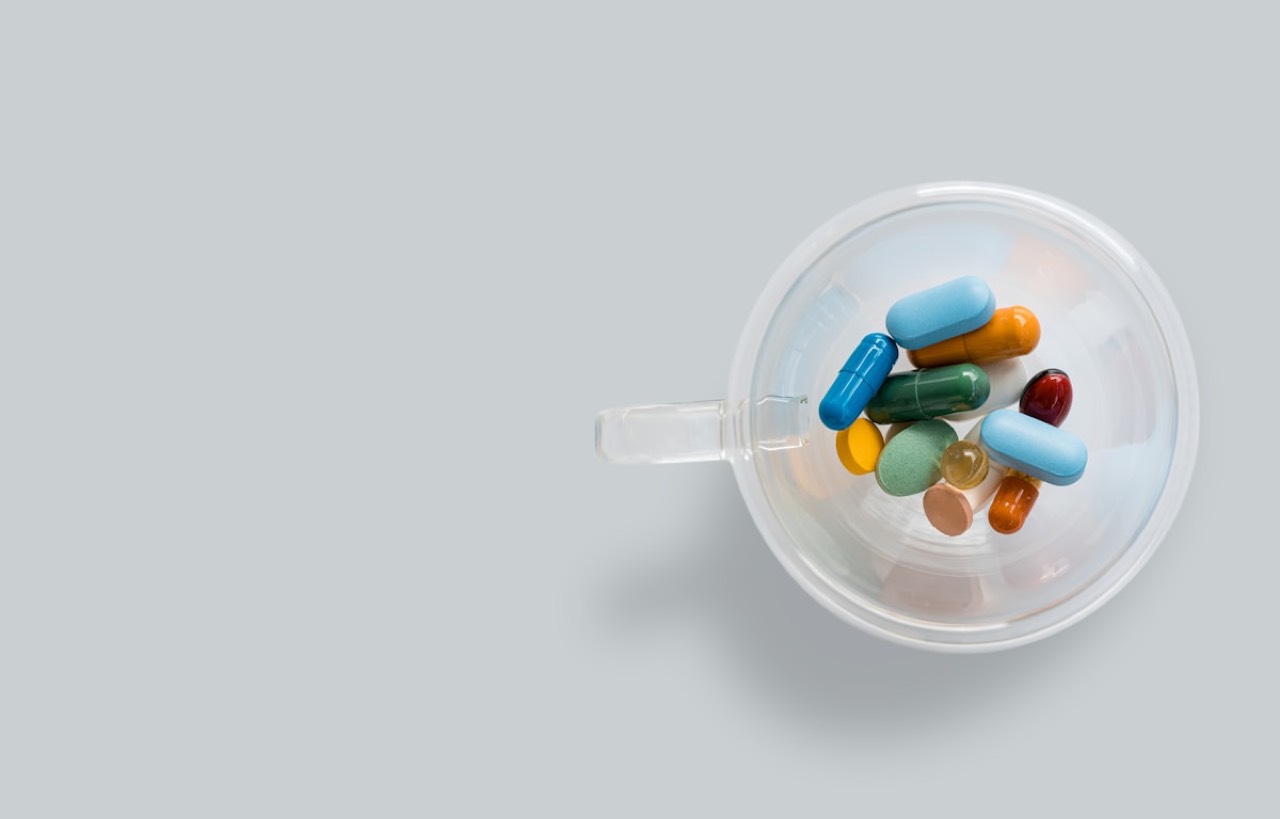 Assorted colorful capsules and softgels in a clear cup