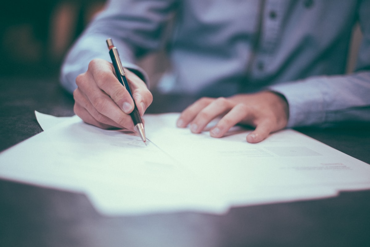 A person signing a printed document with a pen