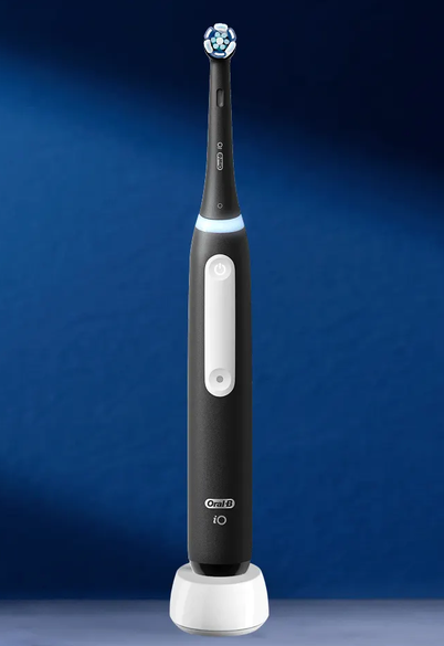 Oral-B iO handle standing on its charging base against a deep blue backdrop