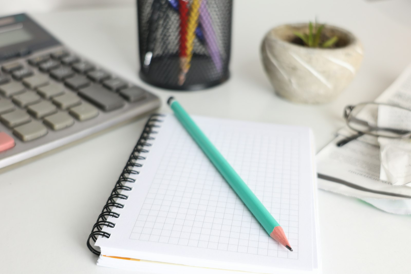 Desk set up for small-business bookkeeping with a calculator and notebook