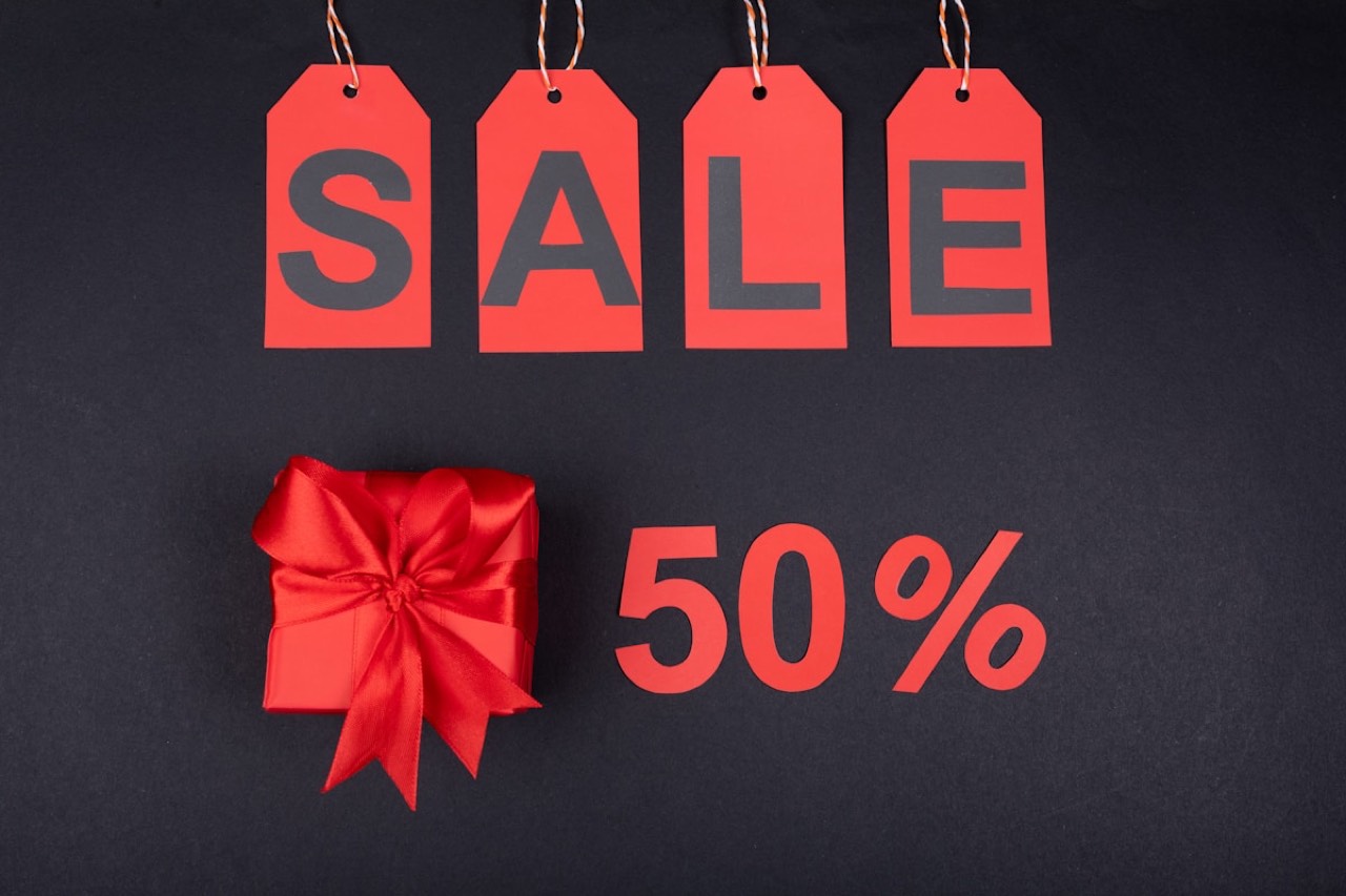 Red sale tags and a gift box marked 50% off on a dark background