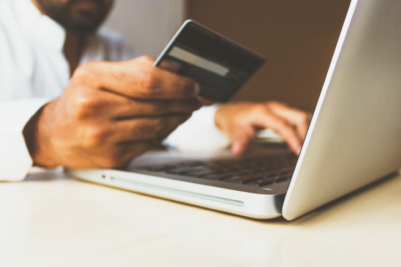 Person shopping online with a laptop and a credit card in hand