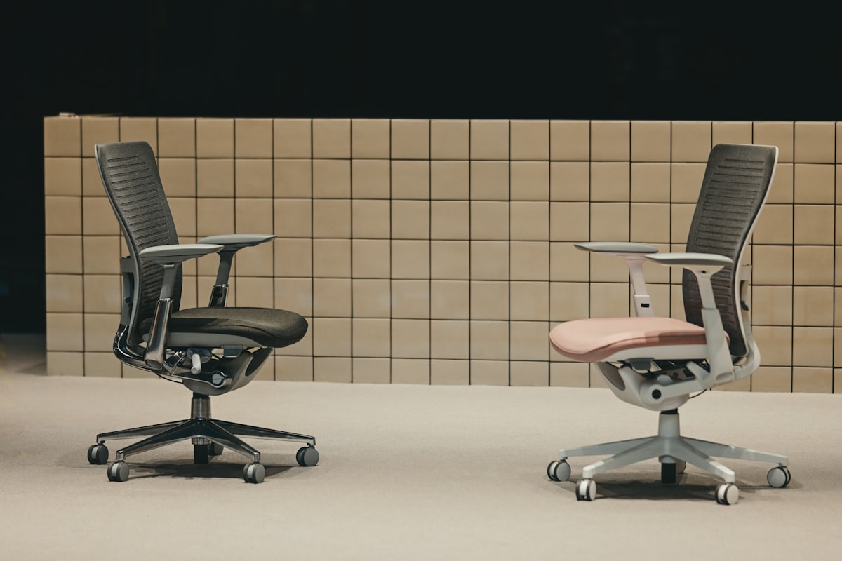Two ergonomic office chairs, dark and light, facing each other