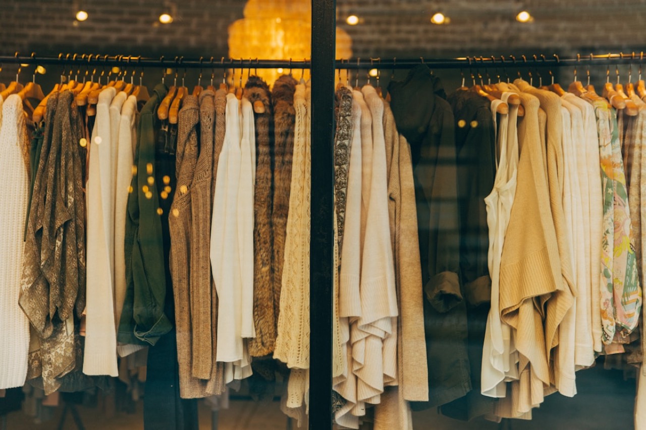 Neatly hung designer tops against a brick wall