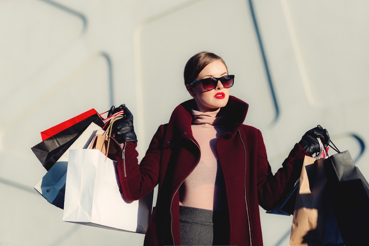 Woman in a red coat carrying designer shopping bags